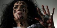 Eine Frau, die das Datum 7.10. mit blutroter Farbe auf ihre Stirn geschrieben hat, fordert die Freilassung der Geiseln der Hamas