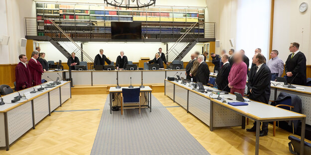 Die Mitglieder der Terrorgruppe „Vereinte Patrioten“ stehen im Verhandlungssaal in Koblenz zwischen ihren Anwälten.