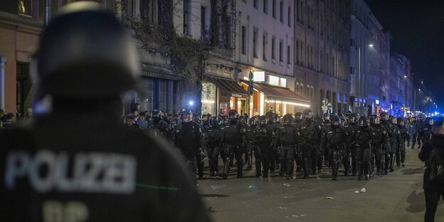 Eine große Gruppe Polizist:innen in Helmen und Riotgear läuft am Abend des 1. Mais 2023 durch Kreuzberg.